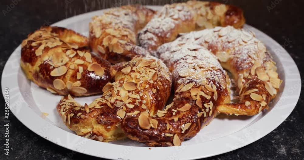 Zooming in SPEED UP shot of beautiful delicious almond croissants ready in a metal tray being powdered with refined sugar- 4K shot at 60pfs Zooming in SPEED UP shot of beautiful delicious almond croissants ready in a metal tray being powdered with refined sugar- 4K shot at 60pfs