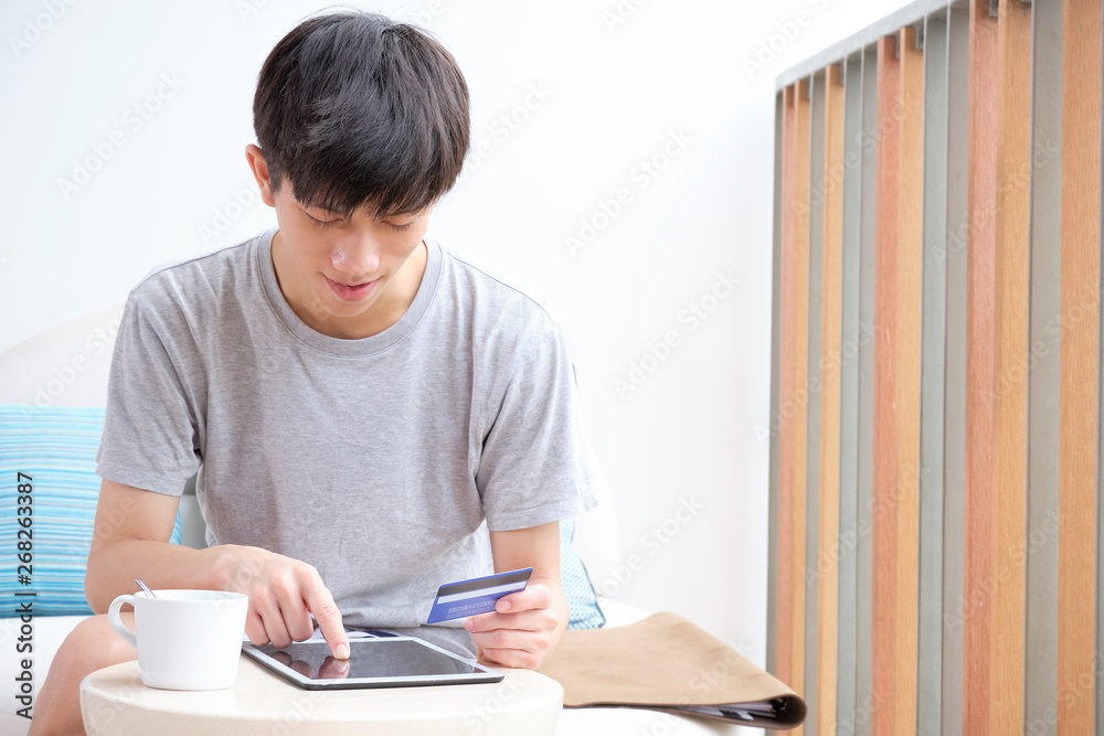 Cute boy holding credit card for shopping online while using tablet in smiling mood. Cute boy holding credit card for shopping online while using tablet in smiling mood.