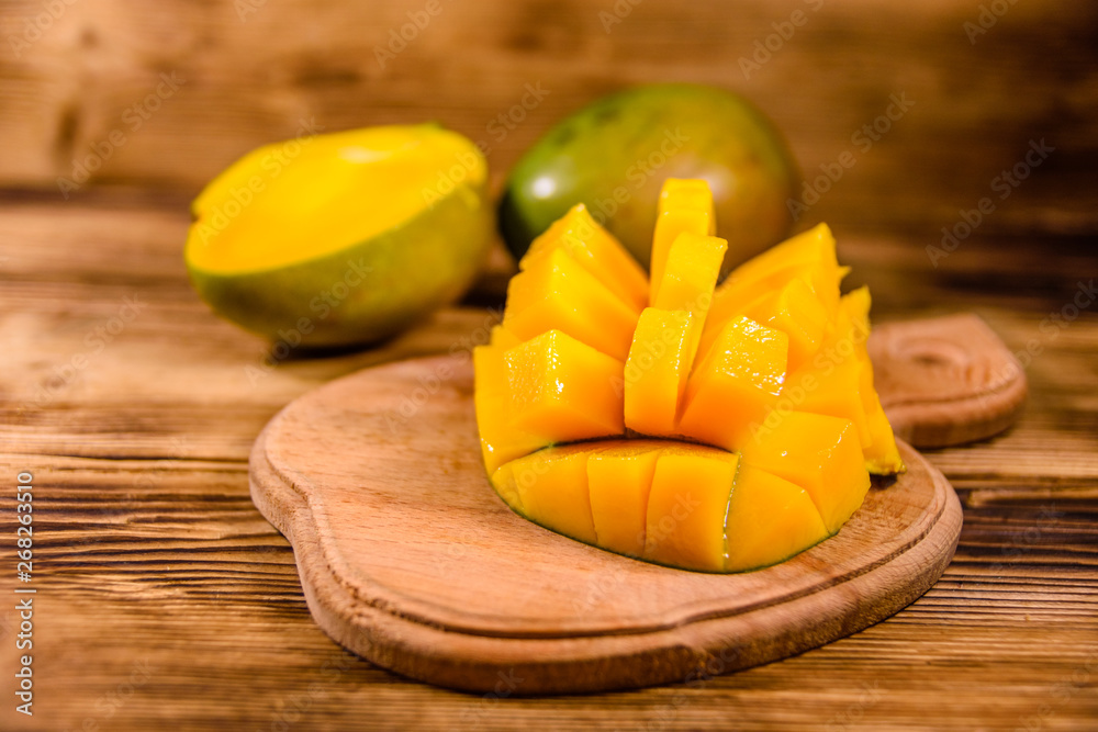 Cutting board with chopped mango fruit on a wooden table Cutting board with chopped mango fruit on a wooden table