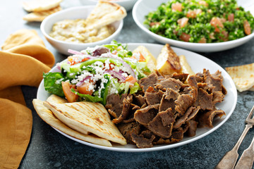Mediterranean food on the table, gyro platter, pita and dips and tabbouleh