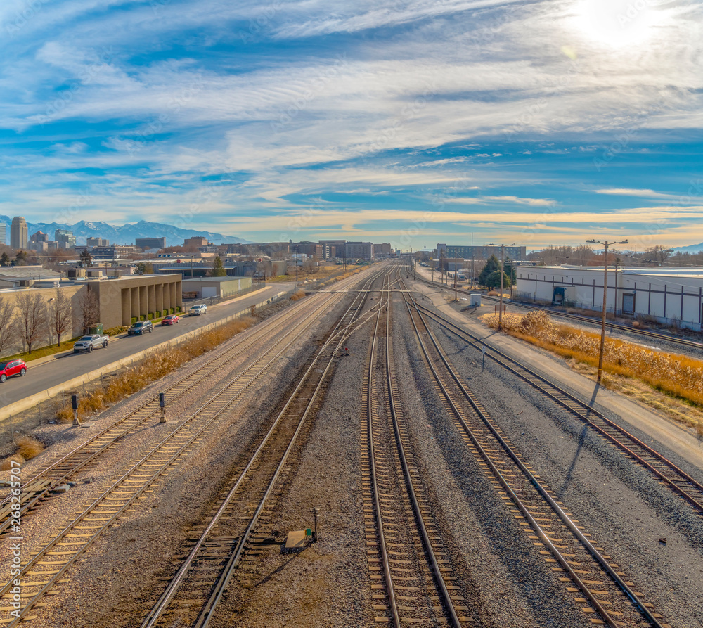 Railroad tracks and roads with mountain and vibrant cloudy blue sky background