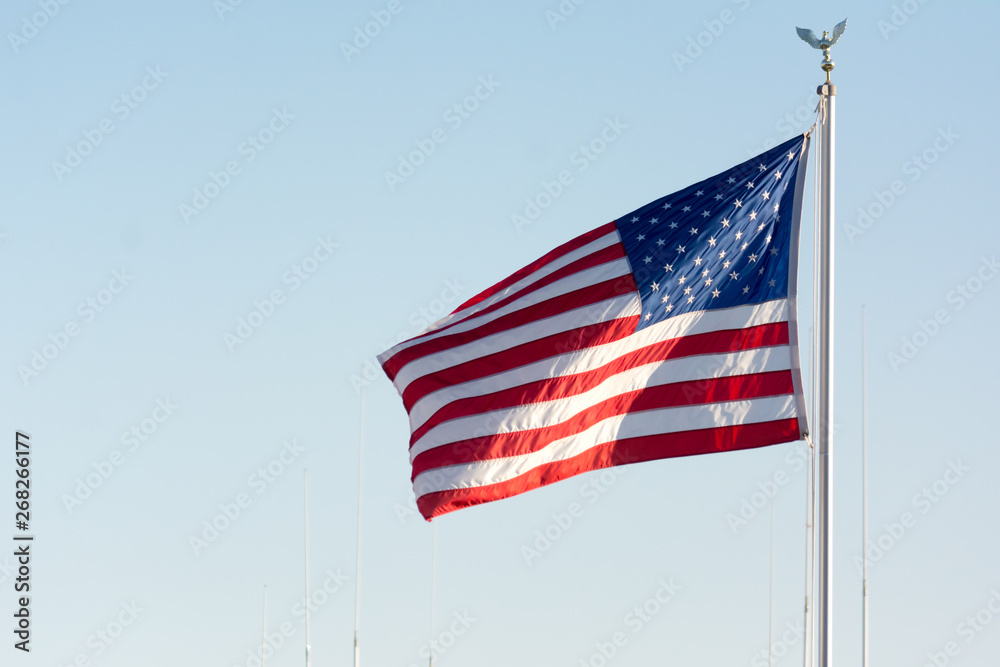Fototapeta premium American National Flag Blowing in the Wind on Blue Sky BAckground