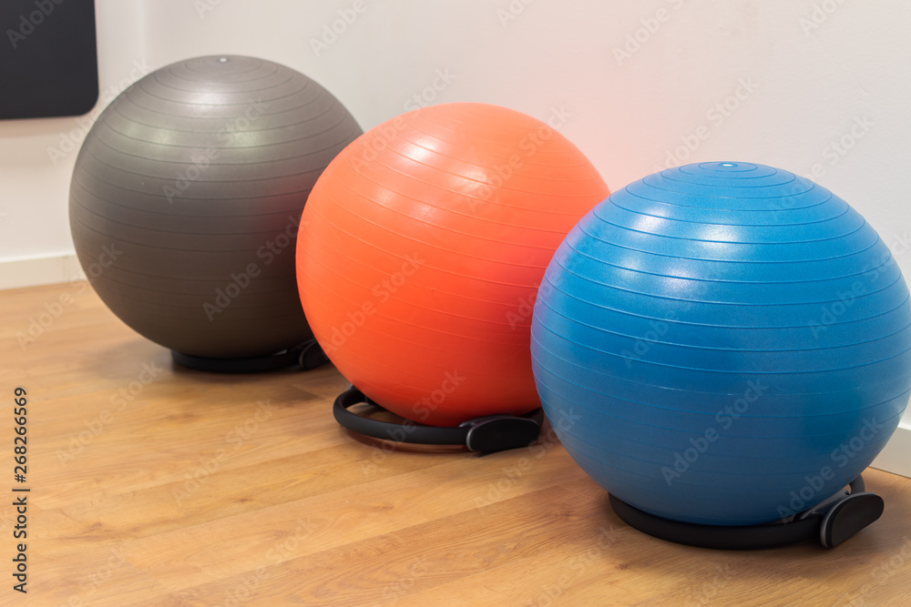 Naklejka premium Fitness balls on wooden floor in the sport center. Exercise with gym balls. Gym for fitness exercises. Colorful fitness equipment on the floor