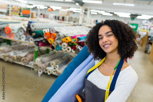 portrait of woman carrying rolls of material in haberdashery shop photo