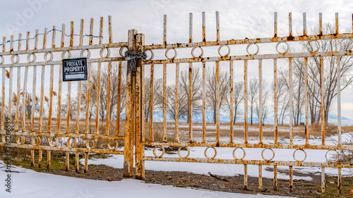 Panorama Private property with a No Trespassing sign on the rusty gate viewed in winter