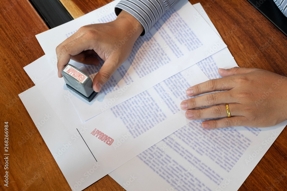 Close-up pictures of the hands of businessmen signing and stamping in approved contract forms Close-up pictures of the hands of businessmen signing and stamping in approved contract forms