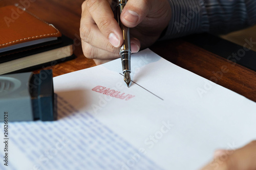 Close-up pictures of the hands of businessmen signing and stamping in approved contract forms