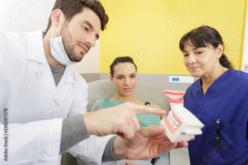 dentist showing jaws model to patient in dental clinic