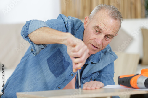 mature man screwing screws into furniture fittings
