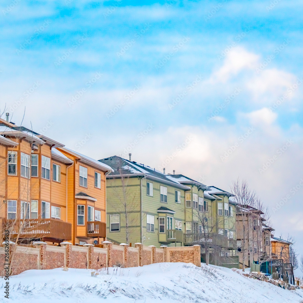 Clear Square Scenic view of colorful houses on a snowy slope beside a paved road in winter