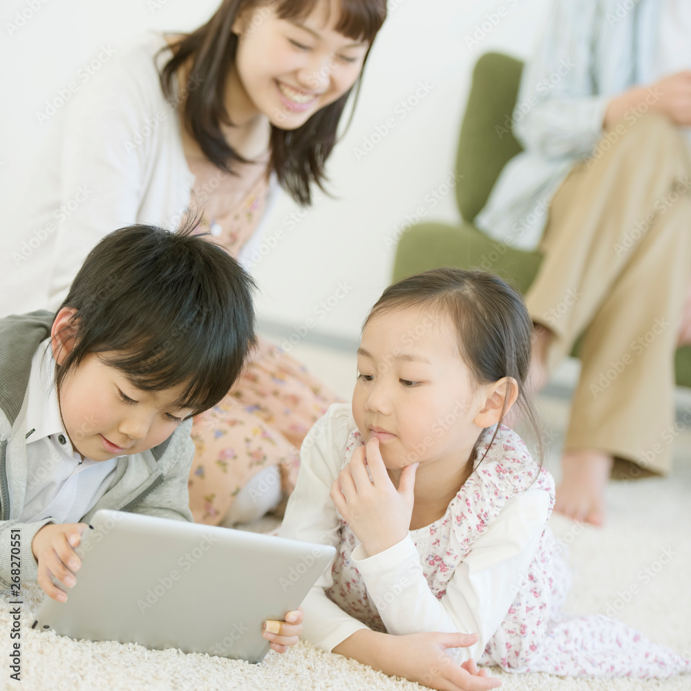 床に寝転びタブレットPCを見る子供たち 床に寝転びタブレットPCを見る子供たち