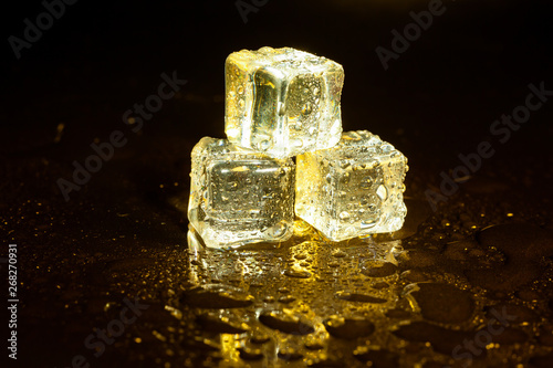 ice cubes on a reflections yellow light. © peterkai