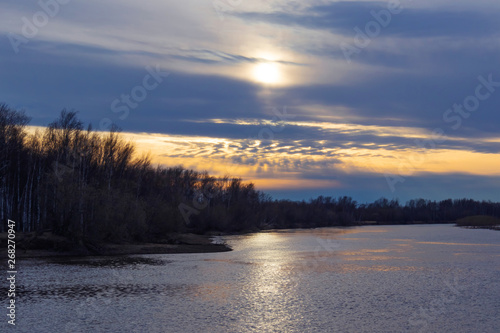 Sunset on the river. Clouds in the sky. New natural image. On the horizon - trees. © Ольга Холявина