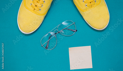 Φωτογραφία yellow sneakers, glasses  and sticker on a green background