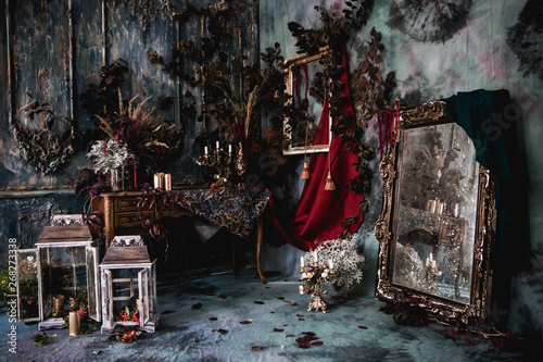 dark decor with dried flowers, vases, chandeliers, textured fabrics against the wall with a golden frame, a wooden table in a luxurious royal Victorian style,candles in old lanterns