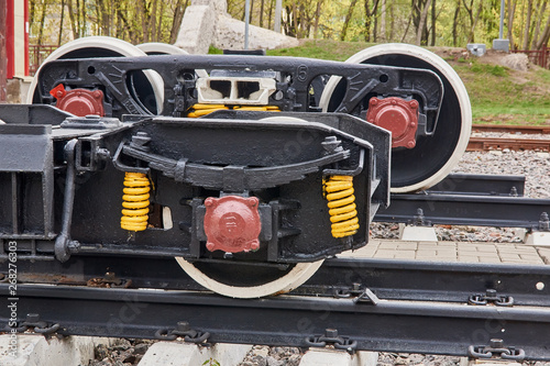Railway wheels narrow gauge railway and ordinary railway. Freight cargo train or boxcar chassis, suspension and metal wheels stand on the rails, close-up