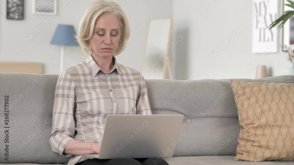 Aged Woman Using Laptop while sitting on Sofa Aged Woman Using Laptop while sitting on Sofa
