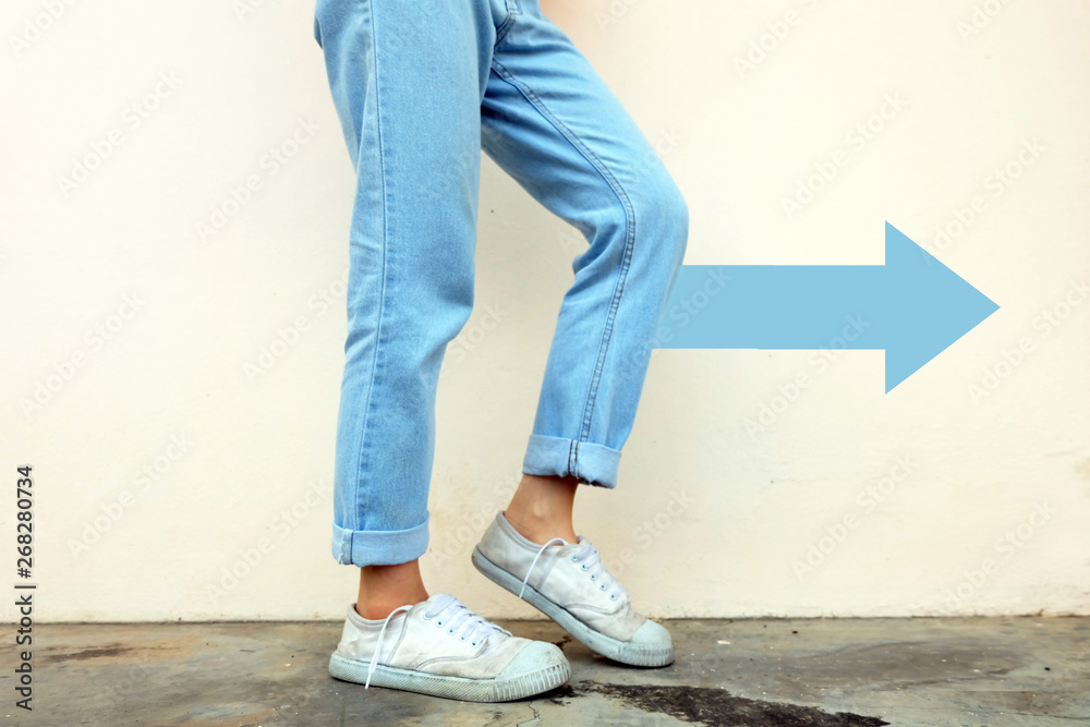 White Shoes Concept. Female Wearing White Sneakers with Blue Arrows Line Direction on Concrete Road Background Great for Any Use. White Shoes Concept. Female Wearing White Sneakers with Blue Arrows Line Direction on Concrete Road Background Great for Any Use.