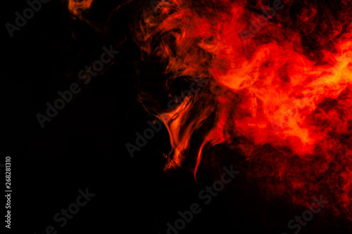 Beautiful horizontal column of smoke in the neon bright light of red, green, yellow and orange on a black background exhaled out of the vape. Nice pattern for printing and backdrop of colored waves.