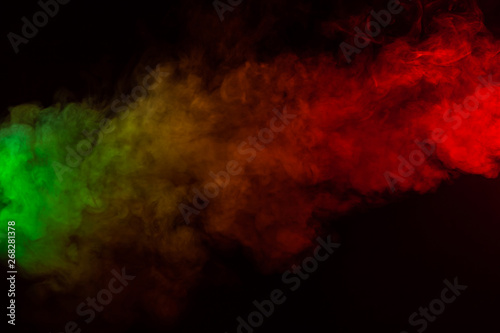 Beautiful horizontal column of smoke in the neon bright light of red, green, yellow and orange on a black background exhaled out of the vape. Nice pattern for printing and backdrop of colored waves.