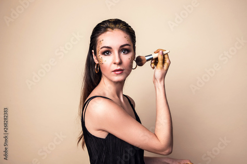 Attractive young woman with glitter make-up and brush.