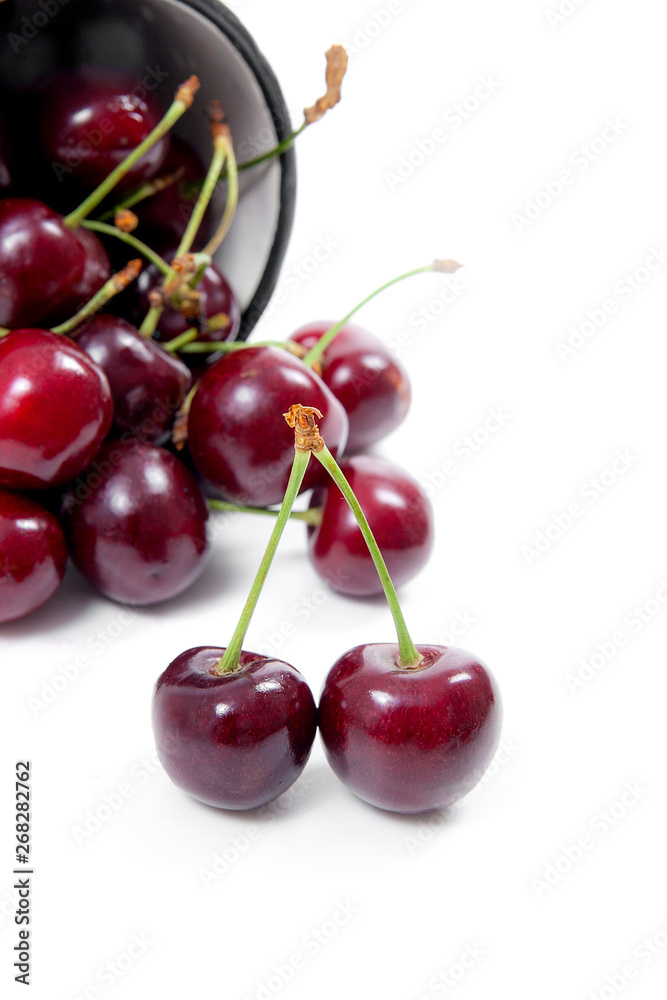 White cup with red sweet cherry isolated on a white background.. White cup with red sweet cherry isolated on a white background..