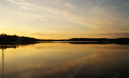 Fototapeta Naklejka Na Ścianę i Meble -  Beautiful sunset on the forest lake. The sun is reflected in the water. Bright contrasting sky.