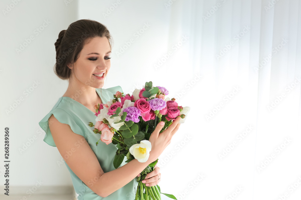 Beautiful young woman with bouquet of flowers at home