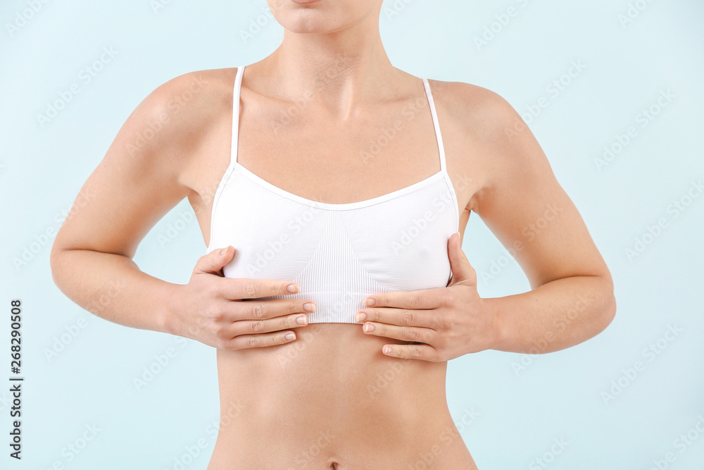 Young woman in underwear on light background. Concept of breast augmentation