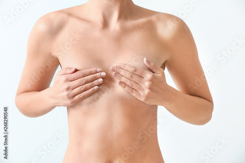 Naked woman on light background. Concept of breast augmentation