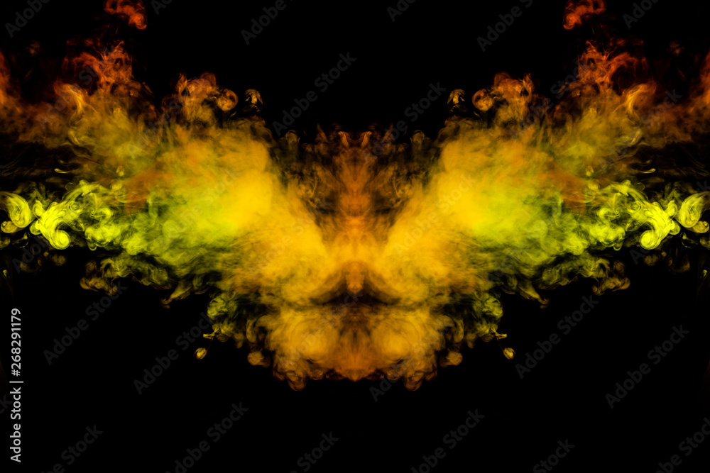 Smoke of different green, yellow, orange and red colors in the form of horror in the shape of the head, face and eye with wings on a black isolated background. Soul and ghost in mystical symbol