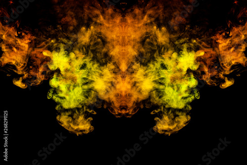 Smoke of different green, yellow, orange and red colors in the form of horror in the shape of the head, face and eye with wings on a black isolated background. Soul and ghost in mystical symbol