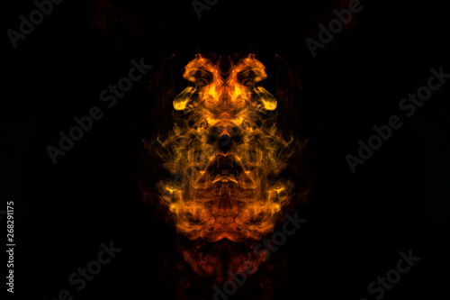 Abstract image of smoke of different green, yellow, orange and red colors in the form of horror in the shape of the head, face and eye on a black isolated background. Soul and ghost in mystical symbol