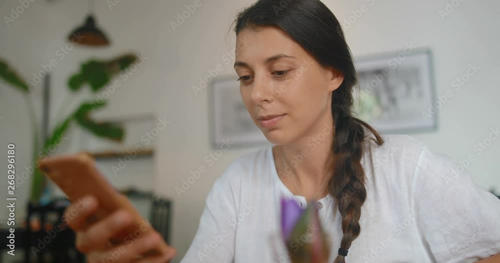 attractive young woman sitting in a cafe uses a smartphone. Shot on Canon 1DX mark2 4K camera attractive young woman sitting in a cafe uses a smartphone. Shot on Canon 1DX mark2 4K camera