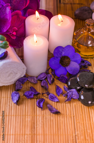 Colorful Spa setting orchid flowers with black stones and oil place for relaxation and wellness