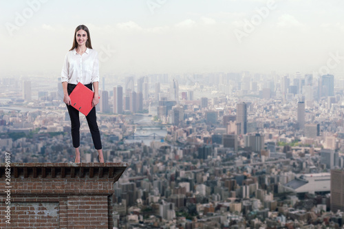 Beautiful businesswoman standing on the rooftop of a skyscraper over a city