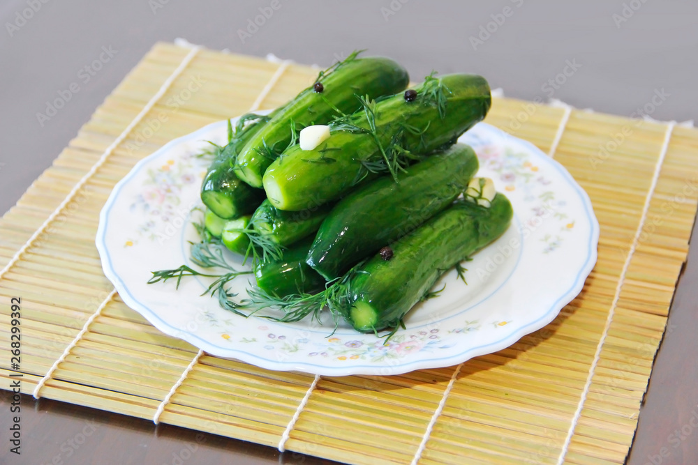salted green cucumbers with dill and seasoning on a white plate salted green cucumbers with dill and seasoning on a white plate