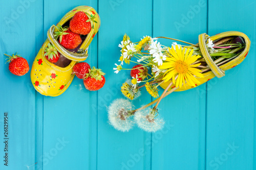Summer background with strawberries and tiny baby shoes
