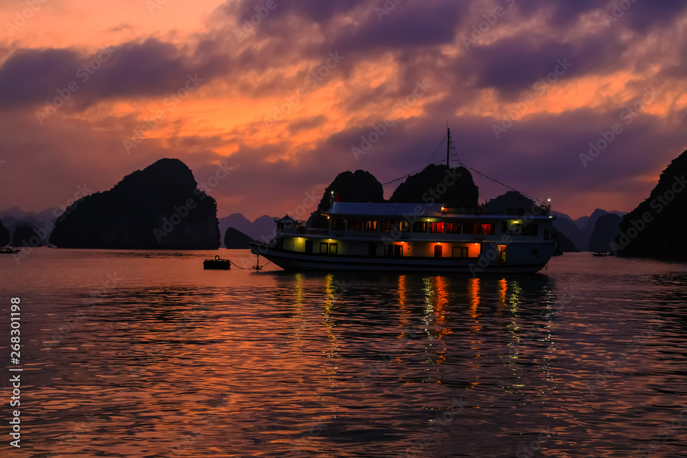 sunset in Halong Bay. Cruise traditional ship wooden junk sailing Ha Long Bay, Vietnam UNESCO World Heritage Site.