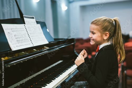 Fototapete happy little girl teaching to play piano in music school