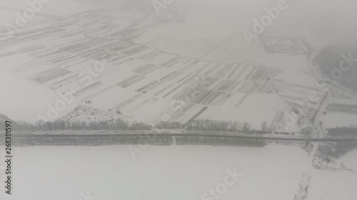 Birdseye view of the large rural fields covered with snow in the countryside. Magnificent landscape with snow flurries and fog. photo