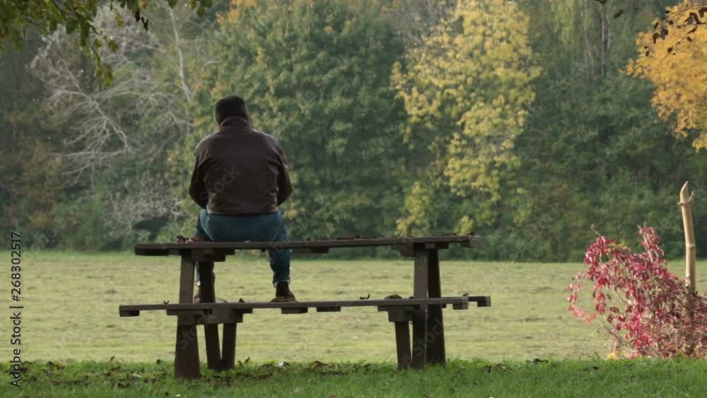 back view of lonely man, panning shot of sad person sitting on a bench back view of lonely man, panning shot of sad person sitting on a bench