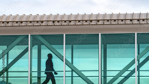 Obraz na płótnie Panorama Silhouette of a man walking inside a skybridge connecting buildings