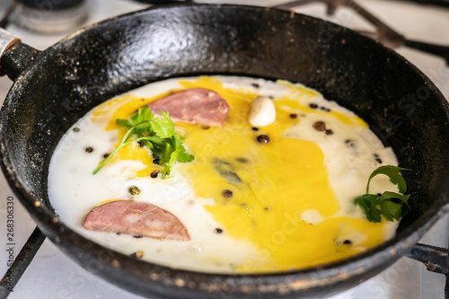 close up process of cooking scpambled eggs in a hot oiled frying pan with pepper and herbss