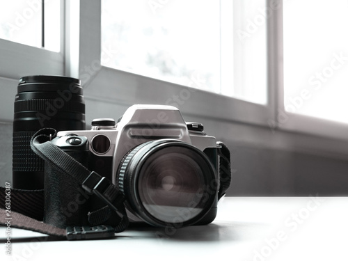 old vintage camera and lens placed on a white table And looks like a digital dslr or film.