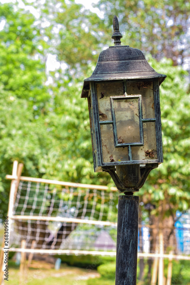 Old pole head lamp on green garden background