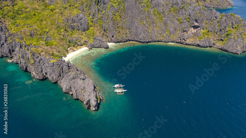 White sand beach and azure lagoon.Tourist boats at tropical islands.El Nido Palawan National Park Philippines.