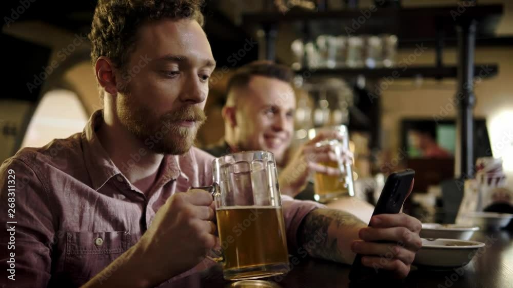 Man with a mobile phone drinking draft beer in a pub Man with a mobile phone drinking draft beer in a pub