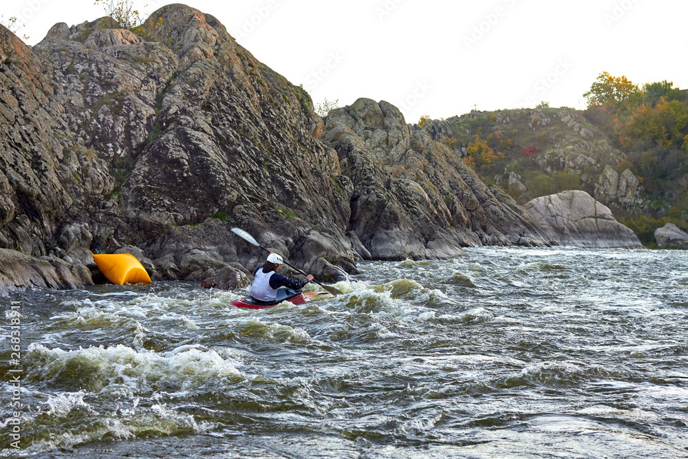Kayak freestyle on whitewater on fast mountain river among the rapids. Whitewater kayaking, extreme water sport.