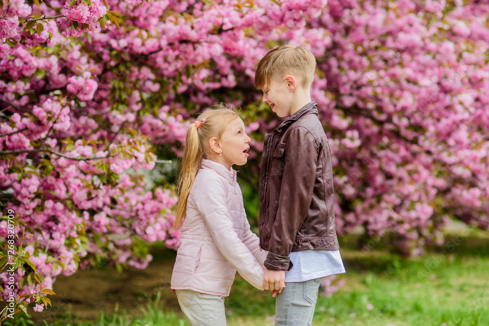 Love is in the air. Tender love feelings. Little girl and boy. Romantic date in park. Spring time to fall in love. Kids in love pink cherry blossom. Couple adorable lovely kids walk sakura garden Love is in the air. Tender love feelings. Little girl and boy. Romantic date in park. Spring time to fall in love. Kids in love pink cherry blossom. Couple adorable lovely kids walk sakura garden